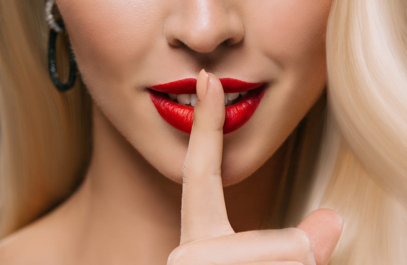 Diskretion beim Escort – blonde Dame mit Verschwiegenheitsgeste